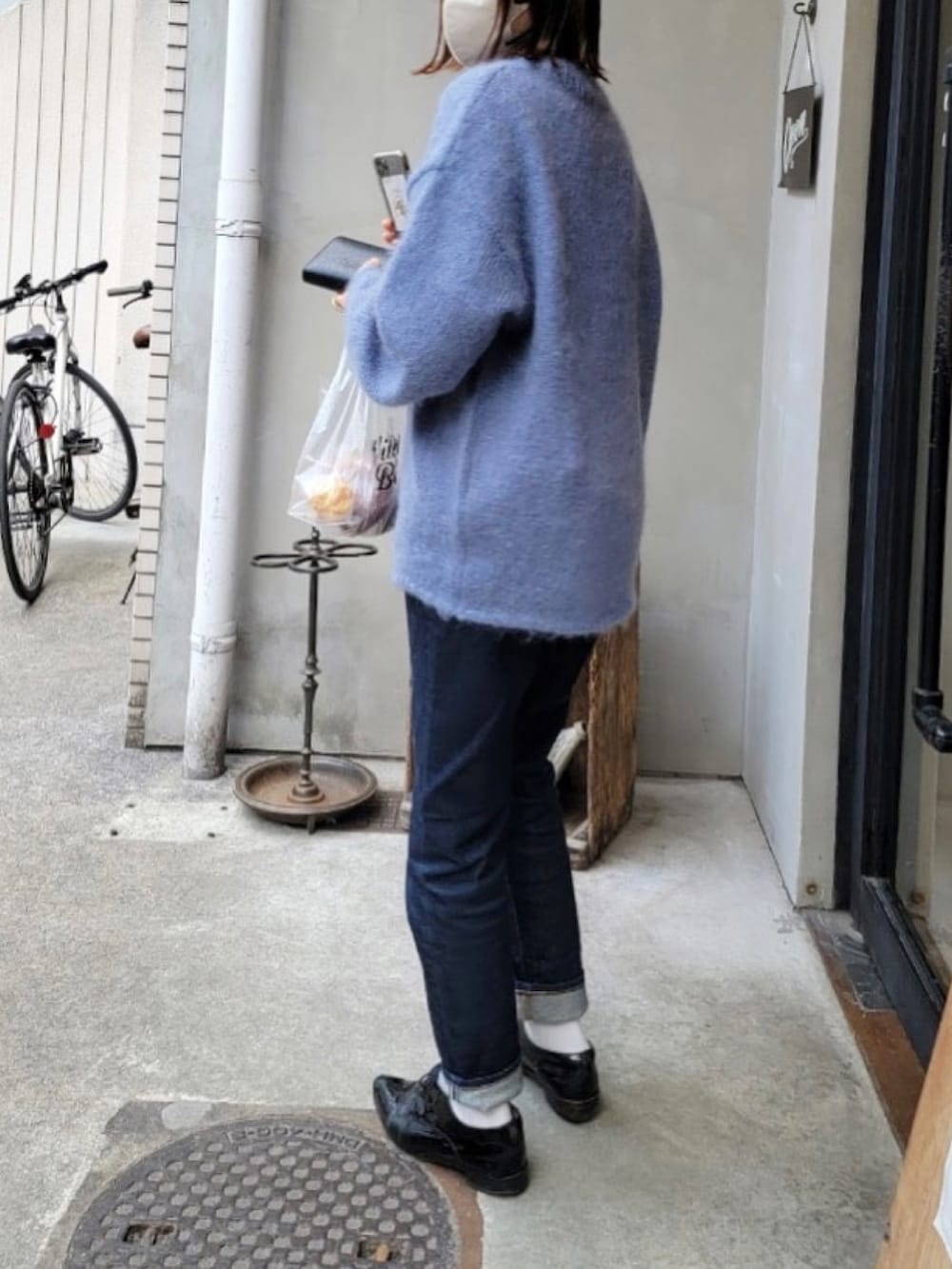 ブルー系のニット/セーター、ブルー系のデニムパンツ、ブラック系の財布を着用したレディースの春コーディネートの2枚目の写真