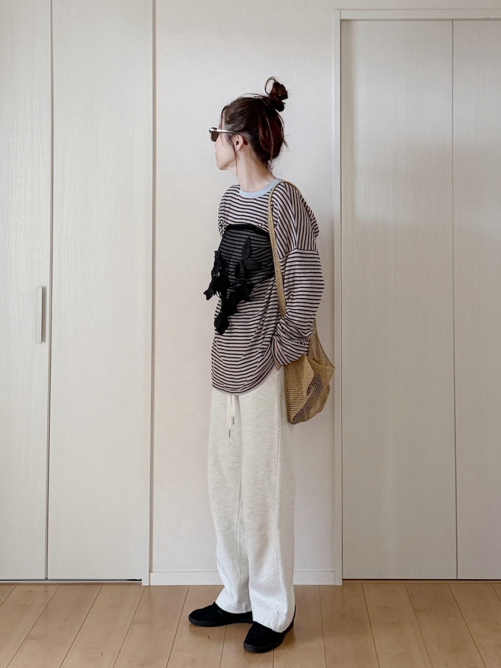 グレー系のニット/セーター、ホワイト系のスウェットパンツ、ベージュ系のショルダーバッグを着用したレディースの春コーディネートの2枚目の写真