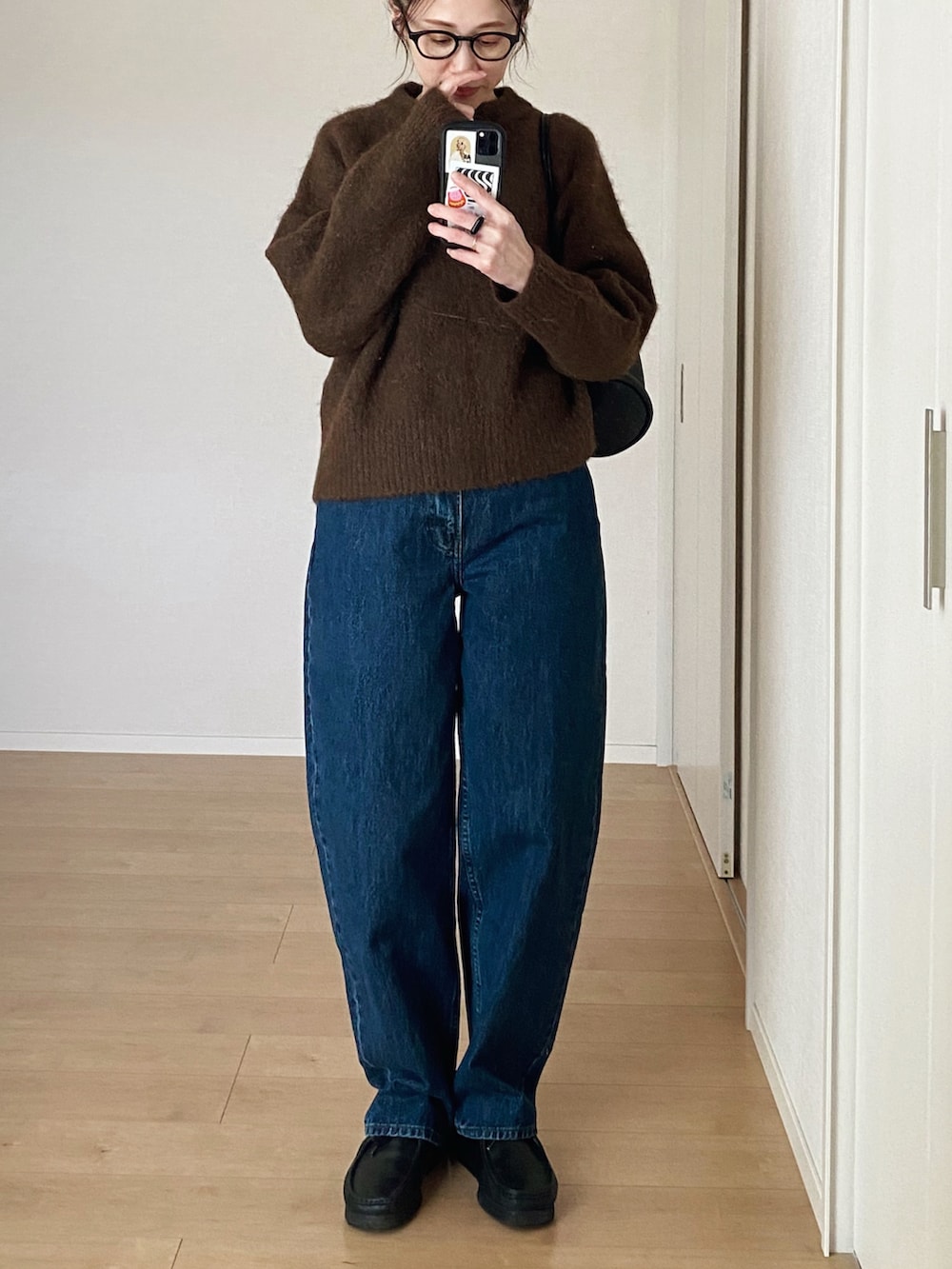 ブラック系のショルダーバッグ、ブラック系のモカシン/デッキシューズ、ブルー系のデニムパンツを着用したレディースの冬コーディネートの3枚目の写真