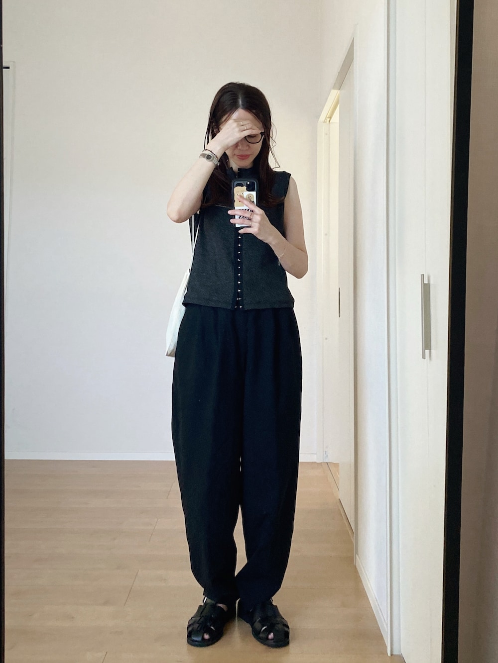 ブラック系のタンクトップ、ブラック系のサンダル、ブラック系のパンツを着用したレディースの秋コーディネートの2枚目の写真