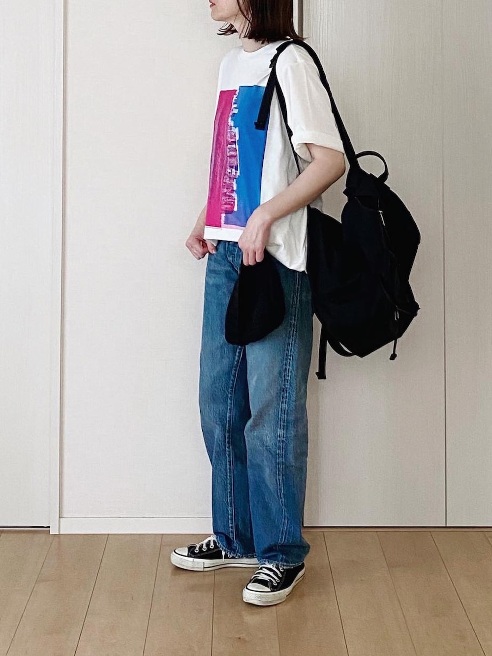 ブラック系のバックパック/リュック、ホワイト系のTシャツ/カットソー、ブルー系のデニムパンツを着用したレディースの夏コーディネートの2枚目の写真
