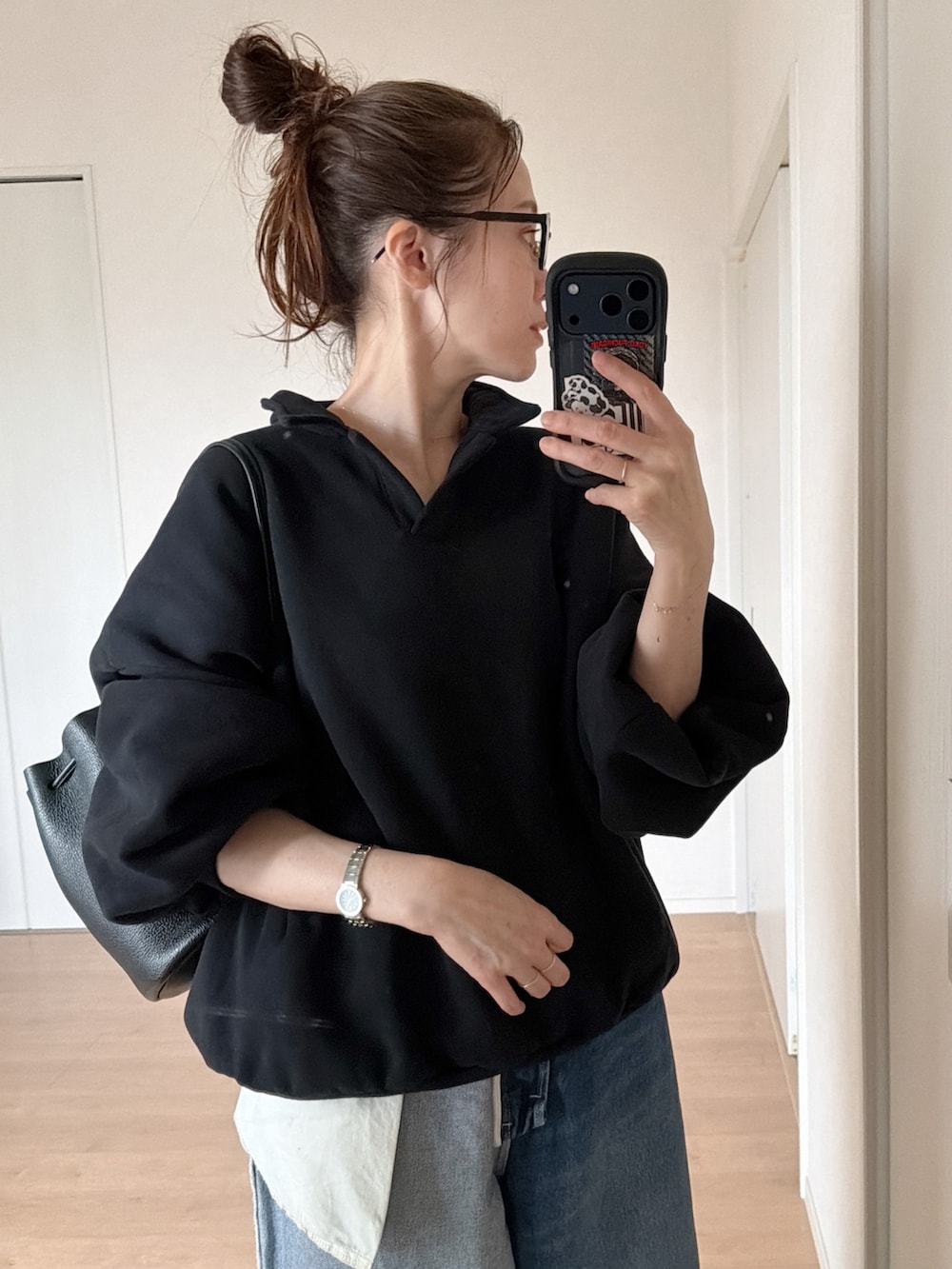 ブラック系のスウェット、ブルー系のデニムパンツ、ブラック系のショルダーバッグを着用したレディースの春コーディネートの3枚目の写真