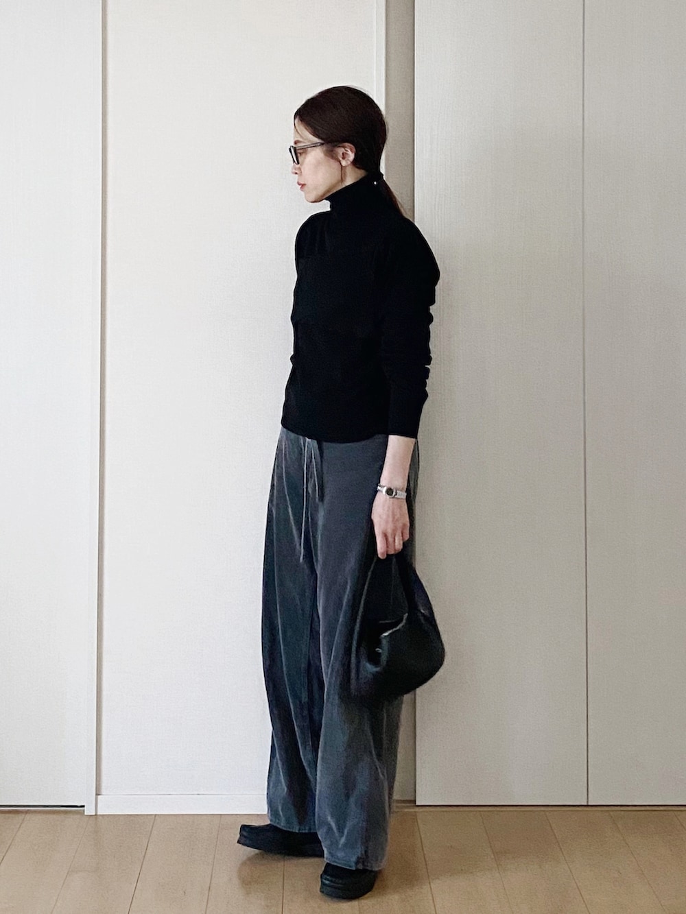 ブラック系のモカシン/デッキシューズ、ブラック系のニット/セーター、ブラック系のキャミソールを着用したレディースの冬コーディネートの3枚目の写真