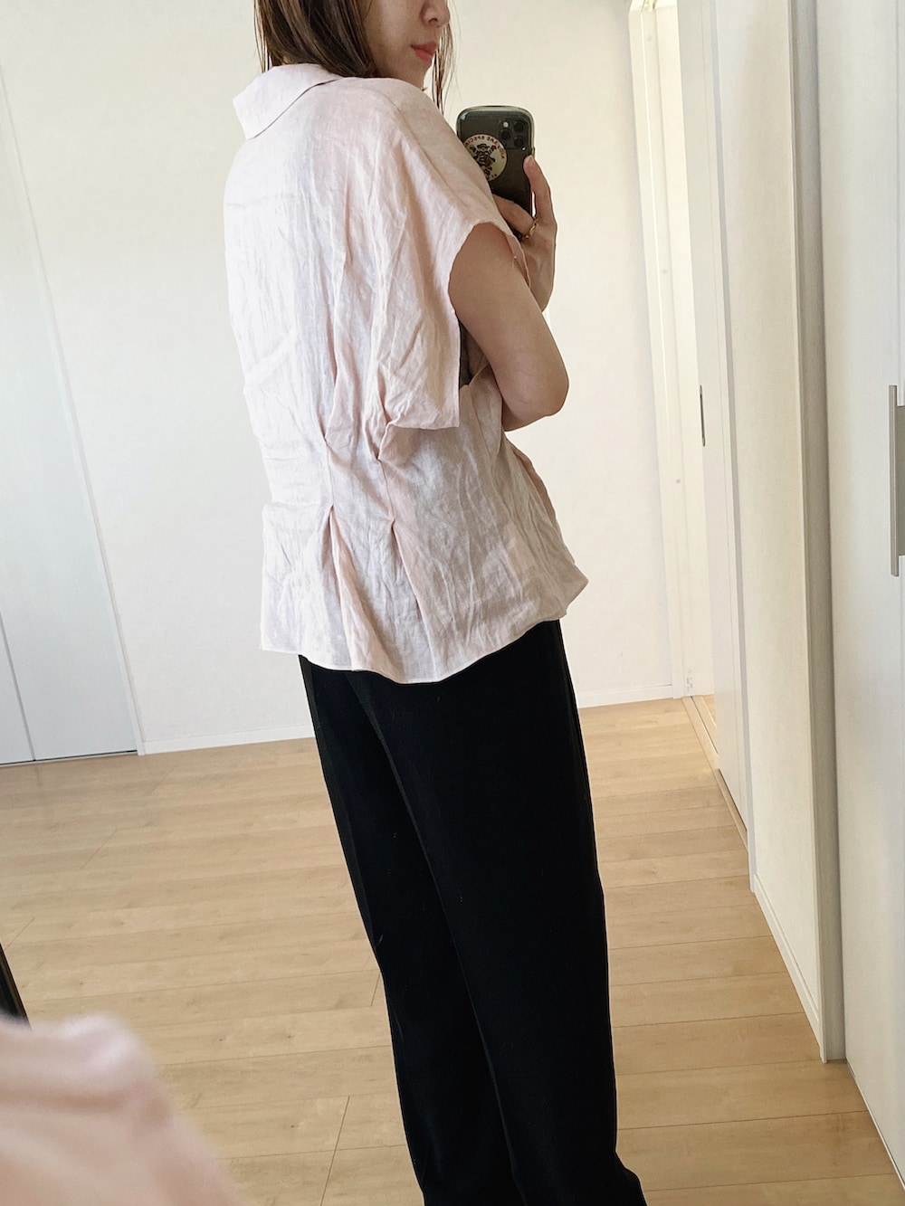 ピンク系のシャツ/ブラウス、ブラック系のハンドバッグ、ブラック系のスラックスを着用したレディースの夏コーディネートの2枚目の写真