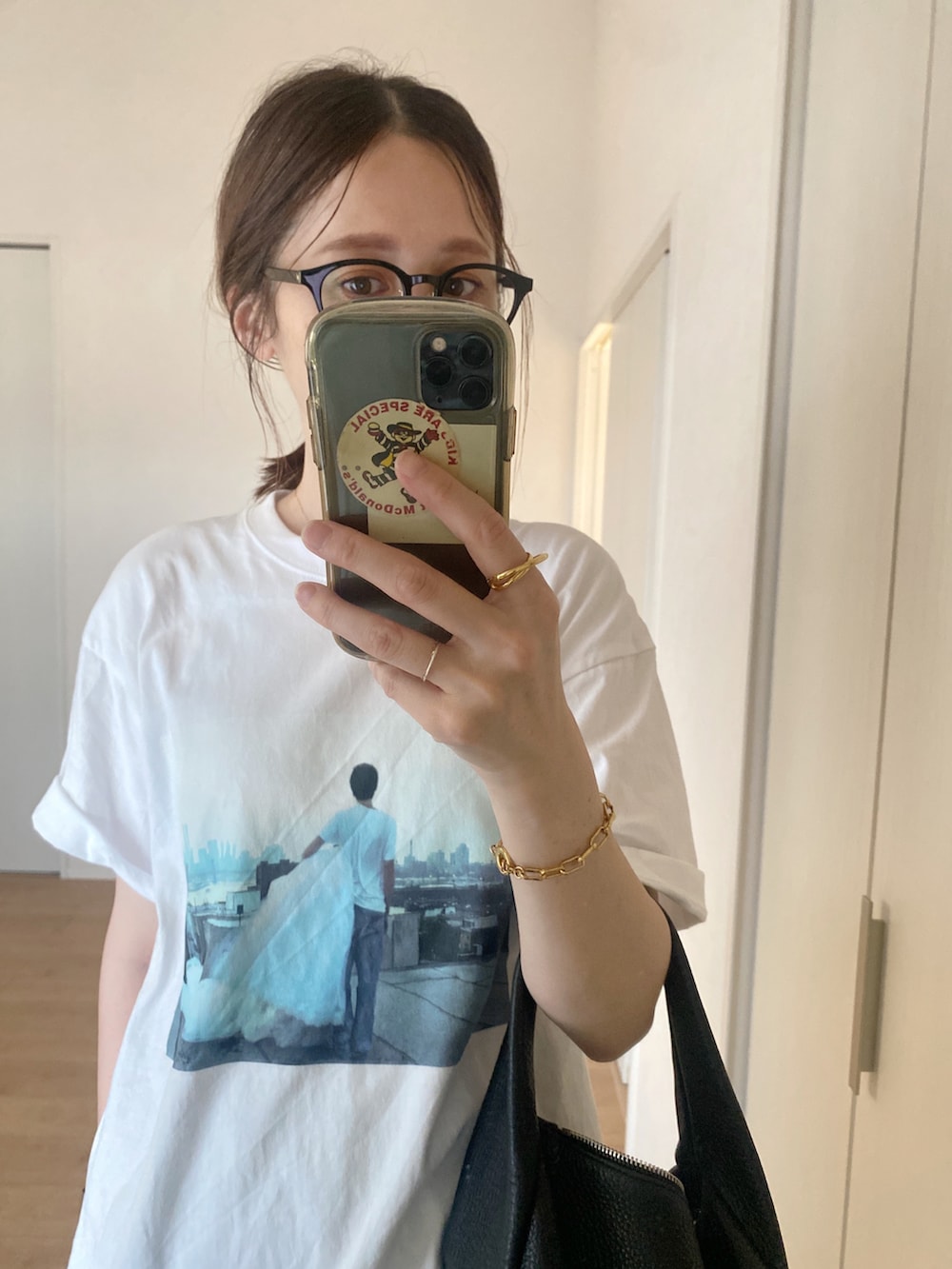 ホワイト系のTシャツ/カットソー、ブラック系のハンドバッグ、ブルー系のデニムパンツを着用したレディースの夏コーディネートの3枚目の写真