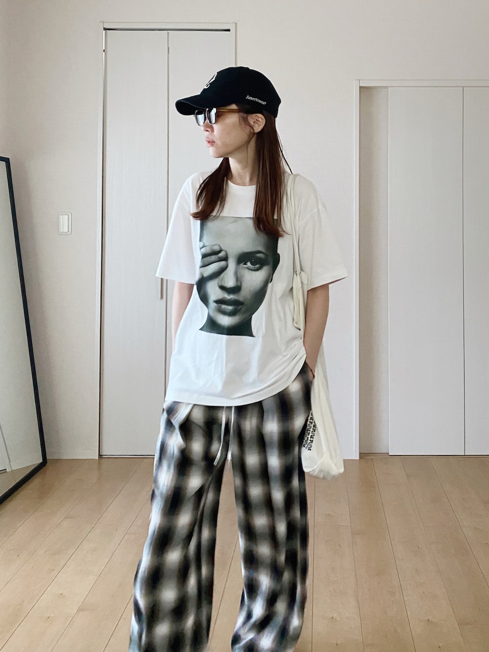 ホワイト系のTシャツ/カットソー、ホワイト系のエコバッグ/サブバッグ、ブラック系のスニーカーを着用したレディースの秋コーディネートの3枚目の写真