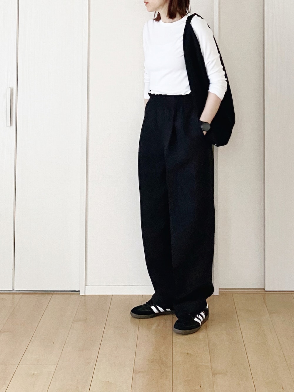 ホワイト系のTシャツ/カットソー、ブラック系のハンドバッグ、ブラック系のスラックスを着用したレディースの春コーディネートの2枚目の写真