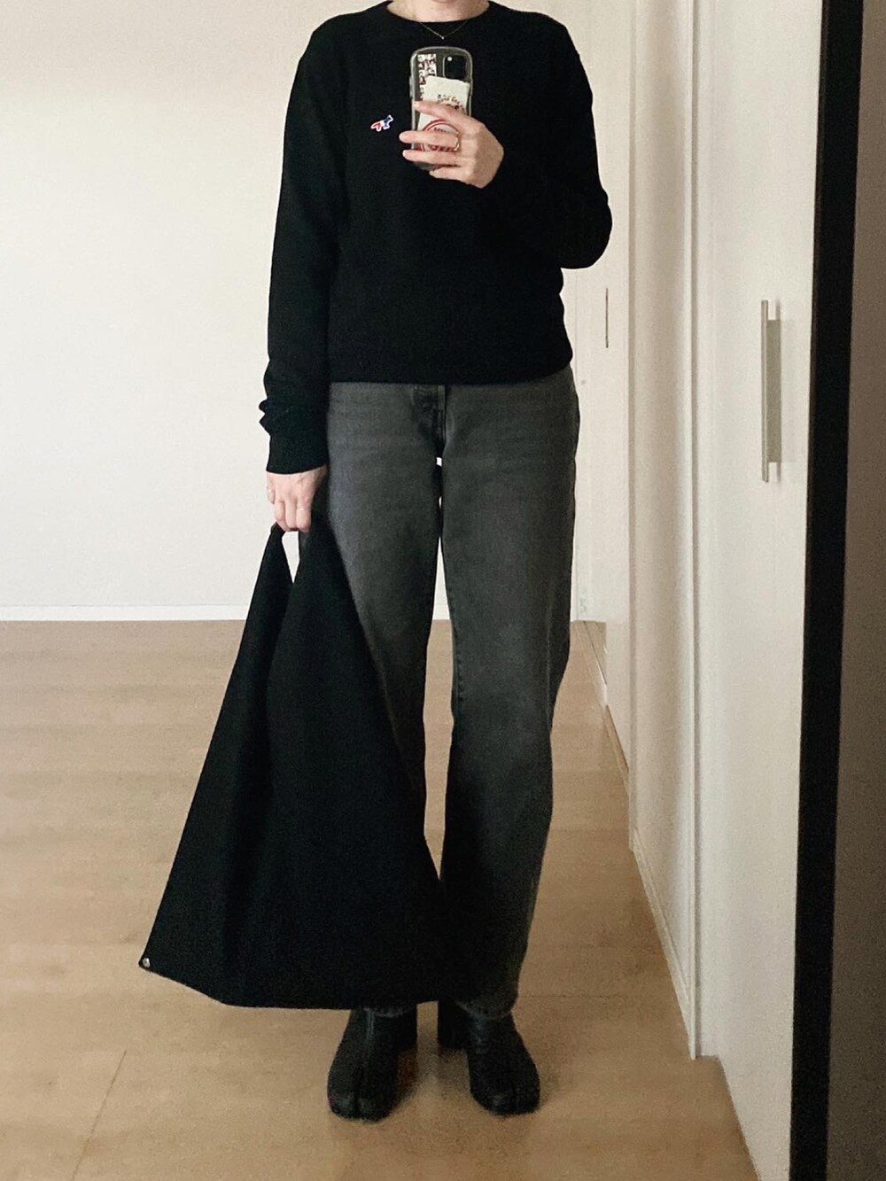 ブラック系のニット/セーター、ブラック系のデニムパンツ、ブラック系のハンドバッグを着用したレディースの冬コーディネートの2枚目の写真