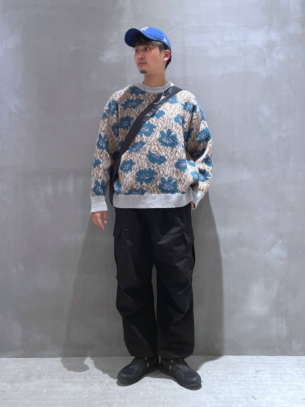 ブルー系のニット/セーター、ブラック系のカーゴパンツ、ブラック系のショルダーバッグを着用したメンズの秋コーディネートの2枚目の写真