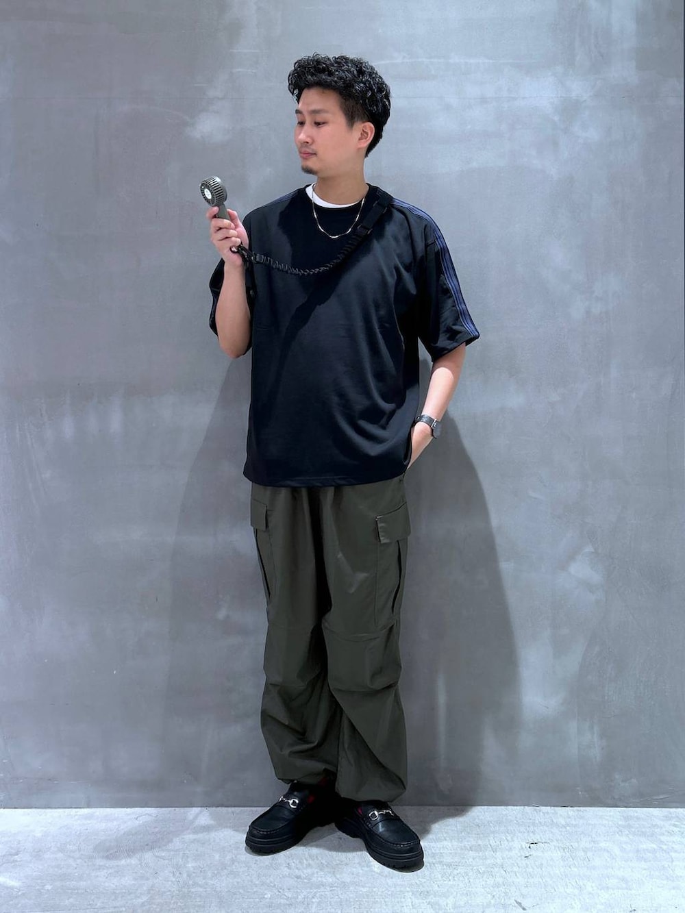 ブラック系のローファー、グリーン系のカーゴパンツ、ブラック系のTシャツ/カットソーを着用したメンズの夏コーディネートの2枚目の写真