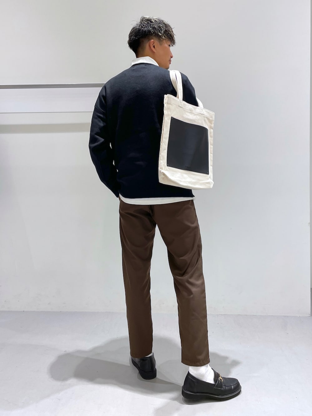 ブラック系のローファー、ホワイト系のTシャツ/カットソー、ブラウン系のスラックスを着用したメンズの冬コーディネートの2枚目の写真