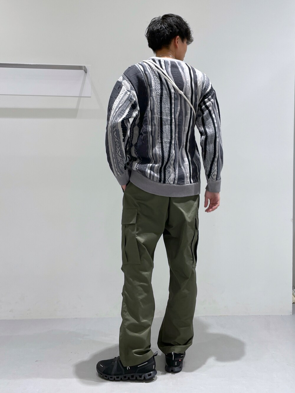グリーン系のその他パンツ、グレー系のニット/セーター、ベージュ系のショルダーバッグを着用したメンズの冬コーディネートの3枚目の写真