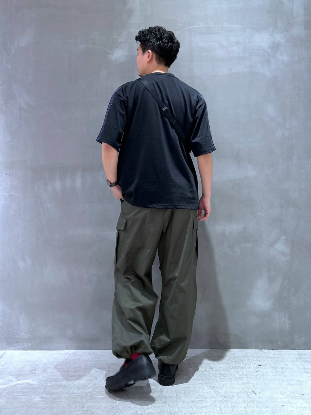 ブラック系のローファー、グリーン系のカーゴパンツ、ブラック系のTシャツ/カットソーを着用したメンズの夏コーディネートの4枚目の写真