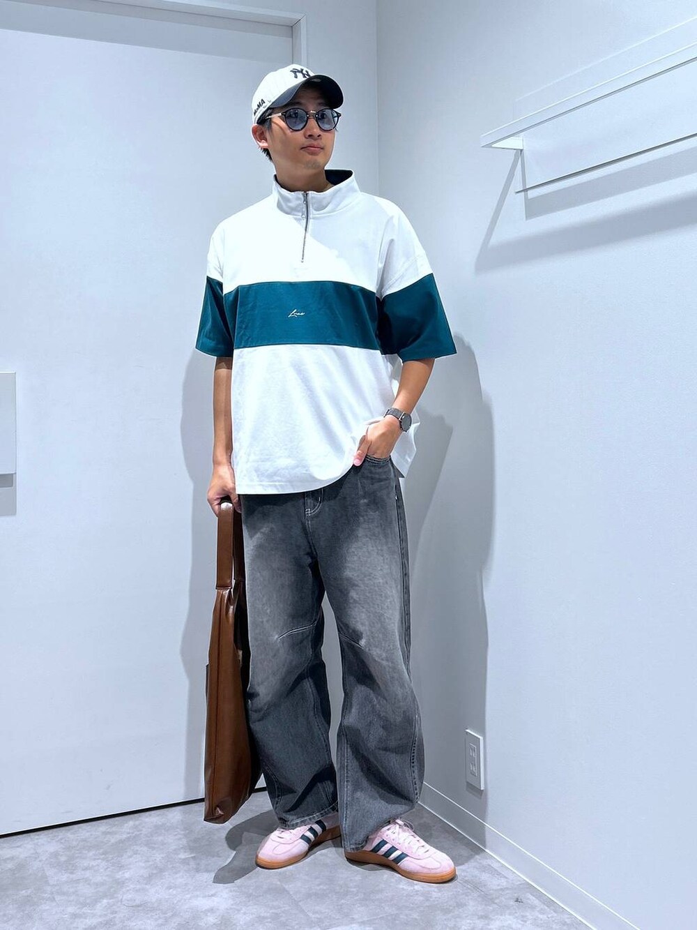 グレー系のデニムパンツ、グリーン系のTシャツ/カットソー、ブラウン系のトートバッグを着用したメンズの春コーディネートの2枚目の写真