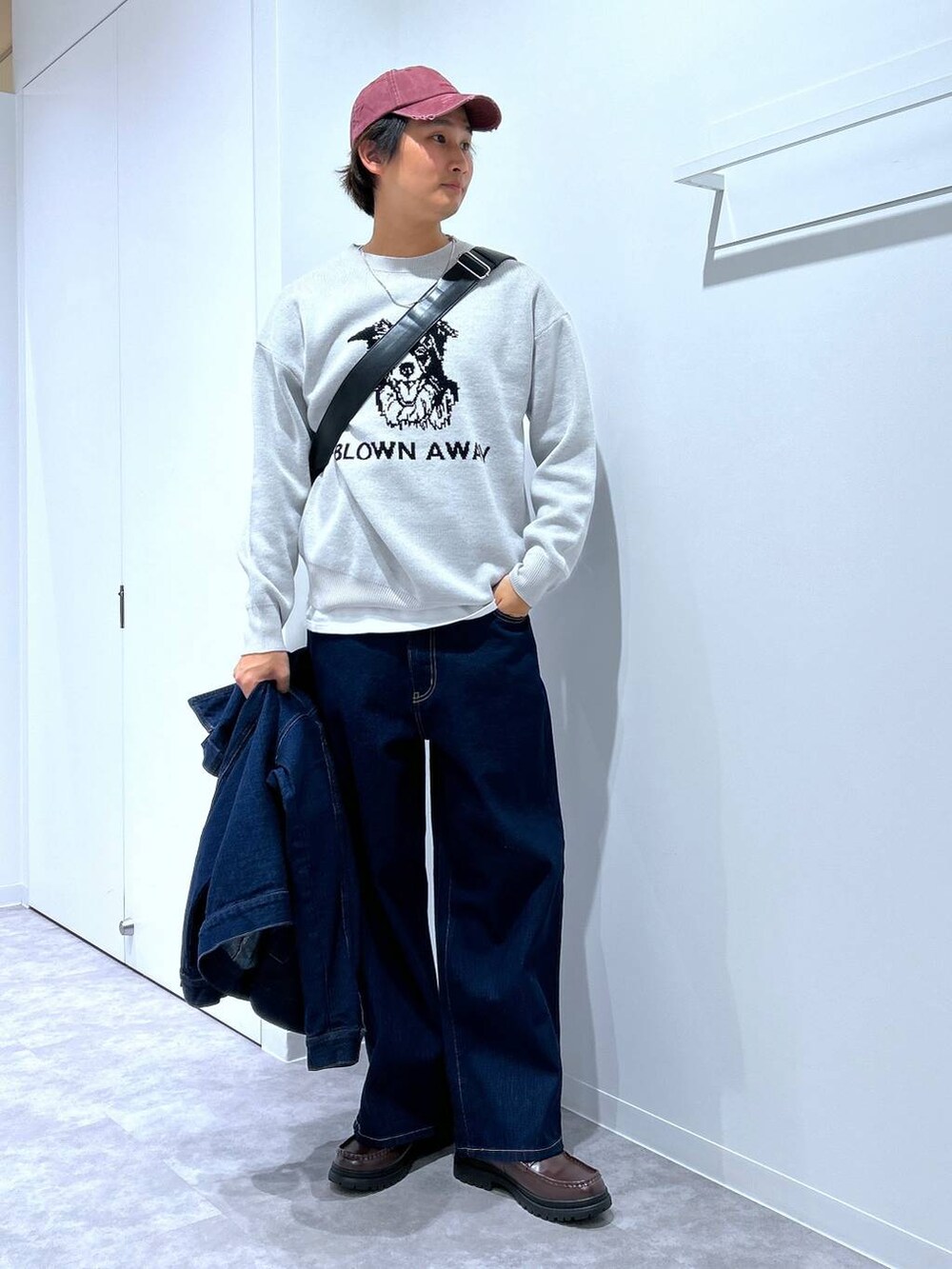 グレー系のニット/セーター、ブラウン系のローファー、ブラック系のショルダーバッグを着用したメンズの冬コーディネートの2枚目の写真