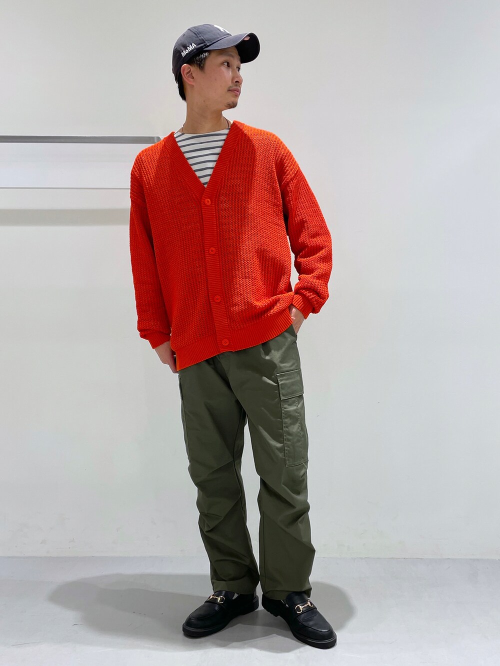 オレンジ系のカーディガン/ボレロ、ベージュ系のTシャツ/カットソー、ブラック系のローファーを着用したメンズの冬コーディネートの2枚目の写真