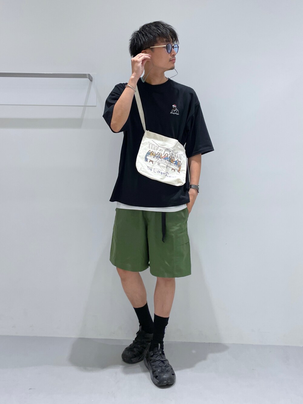 グリーン系のカーゴパンツ、ブラック系のTシャツ/カットソー、その他のショルダーバッグを着用したメンズの夏コーディネートの2枚目の写真