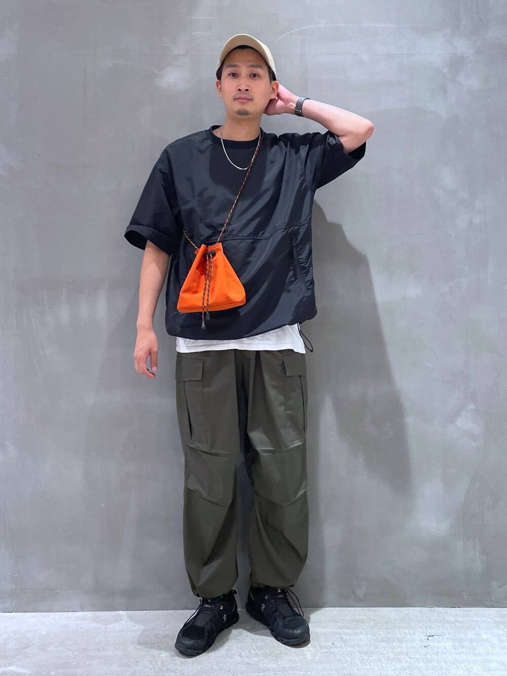 ホワイト系のTシャツ/カットソー、グリーン系のカーゴパンツ、オレンジ系のショルダーバッグを着用したメンズの夏コーディネートの2枚目の写真