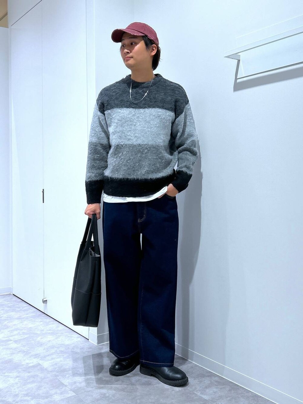 ブラック系のニット/セーター、ブラック系のトートバッグ、ブルー系のデニムパンツを着用したメンズの冬コーディネートの2枚目の写真