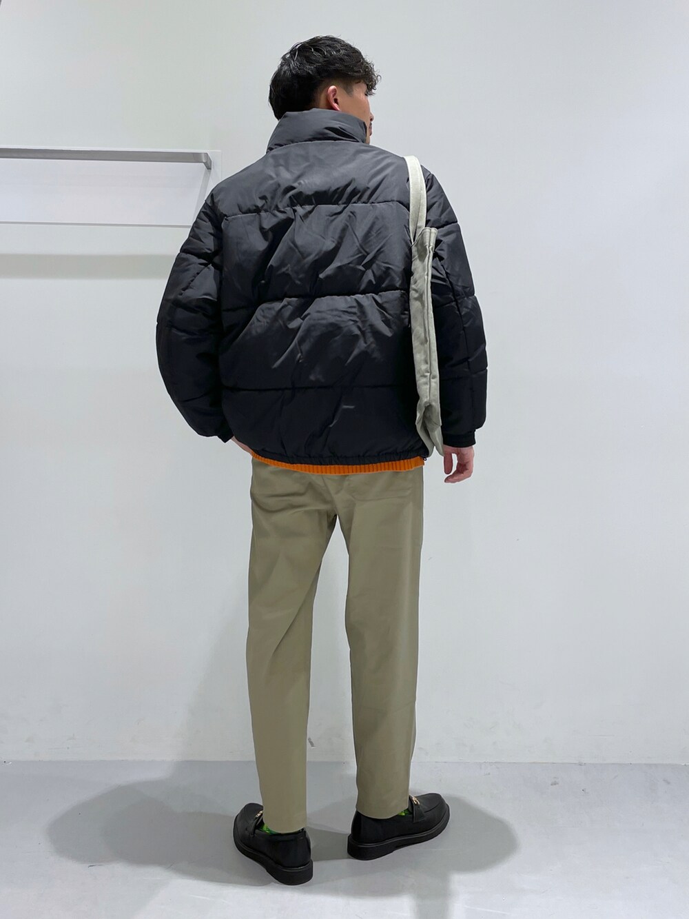 ブラック系のブルゾン、オレンジ系のニット/セーター、ブラック系のローファーを着用したメンズの冬コーディネートの3枚目の写真