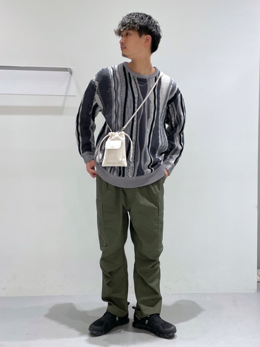 グリーン系のその他パンツ、グレー系のニット/セーター、ベージュ系のショルダーバッグを着用したメンズの冬コーディネートの2枚目の写真
