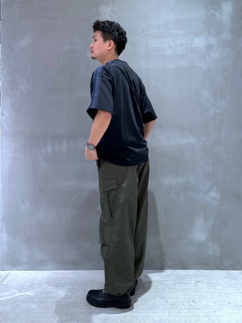 ブラック系のローファー、グリーン系のカーゴパンツ、ブラック系のTシャツ/カットソーを着用したメンズの夏コーディネートの3枚目の写真
