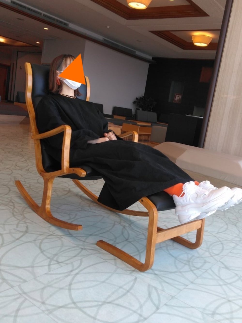 ブルー系のチェスターコート、ホワイト系のスニーカー、ブラック系のワンピースを着用したレディースの冬コーディネートの2枚目の写真