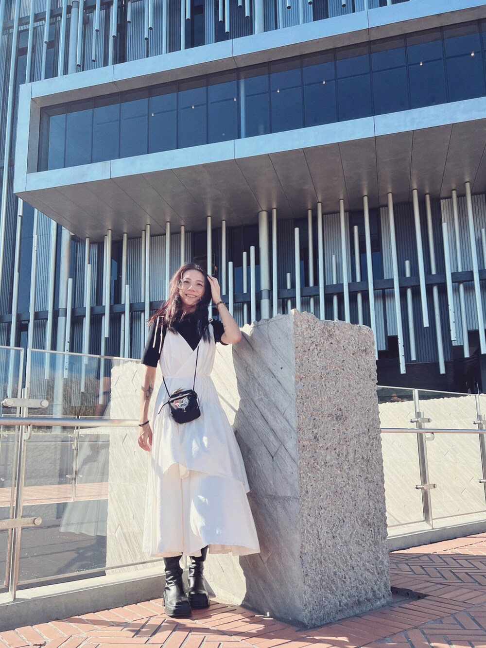 ホワイト系のワンピース、ブラック系のトップス、ブラック系のバッグを着用したレディースの秋コーディネートの2枚目の写真