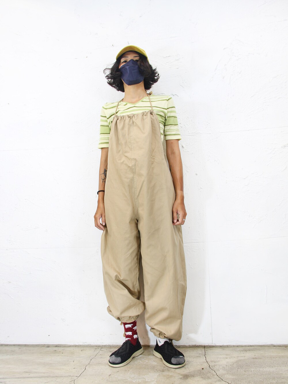 グリーン系のニット/セーター、ベージュ系のサロペット/オーバーオール、イエロー系のキャップを着用したレディースの夏コーディネートの4枚目の写真