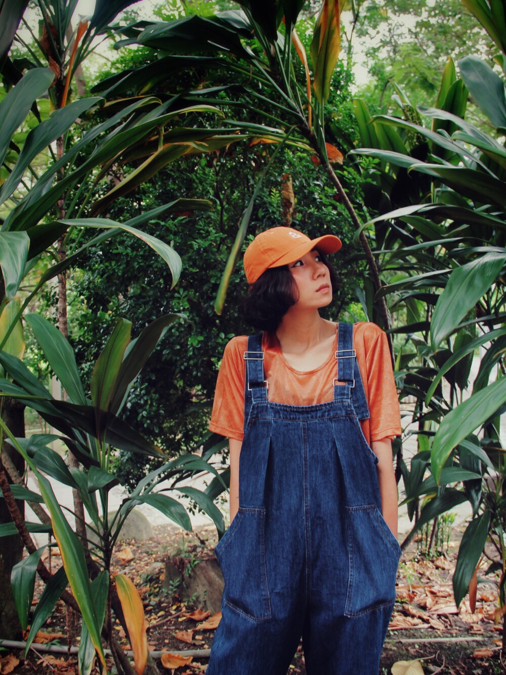 オレンジ系のTシャツ/カットソー、ブルー系のオールインワン・サロペット、オレンジ系のキャップを着用したレディースの夏コーディネートの3枚目の写真