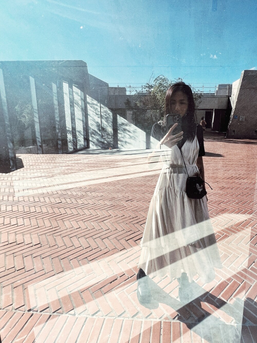 ホワイト系のワンピース、ブラック系のトップス、ブラック系のバッグを着用したレディースの秋コーディネートの3枚目の写真