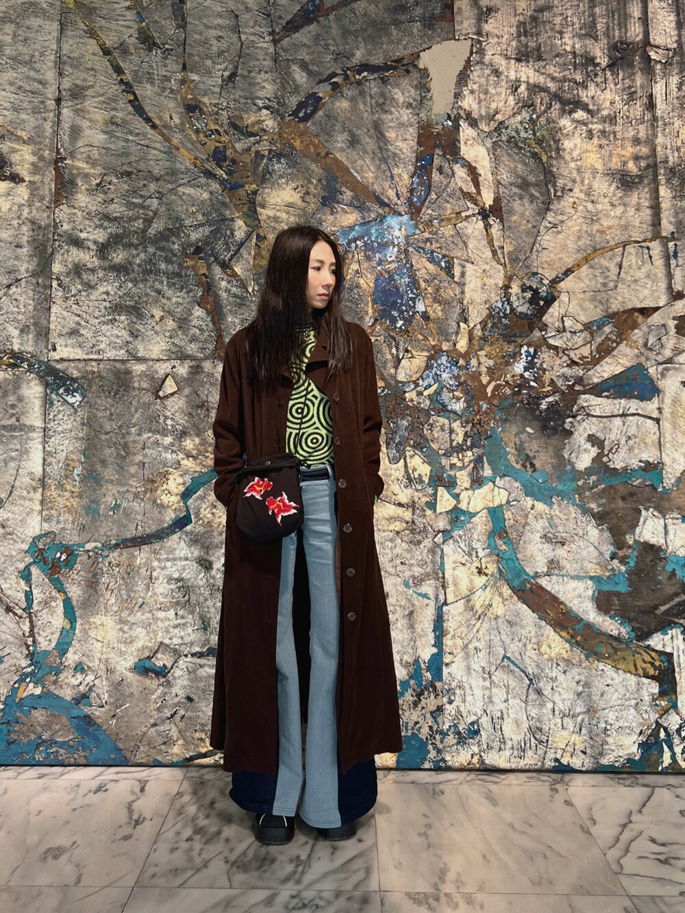 グリーン系のトップス、ブラック系のバッグ、ブルー系のデニムパンツを着用したレディースの春コーディネートの2枚目の写真