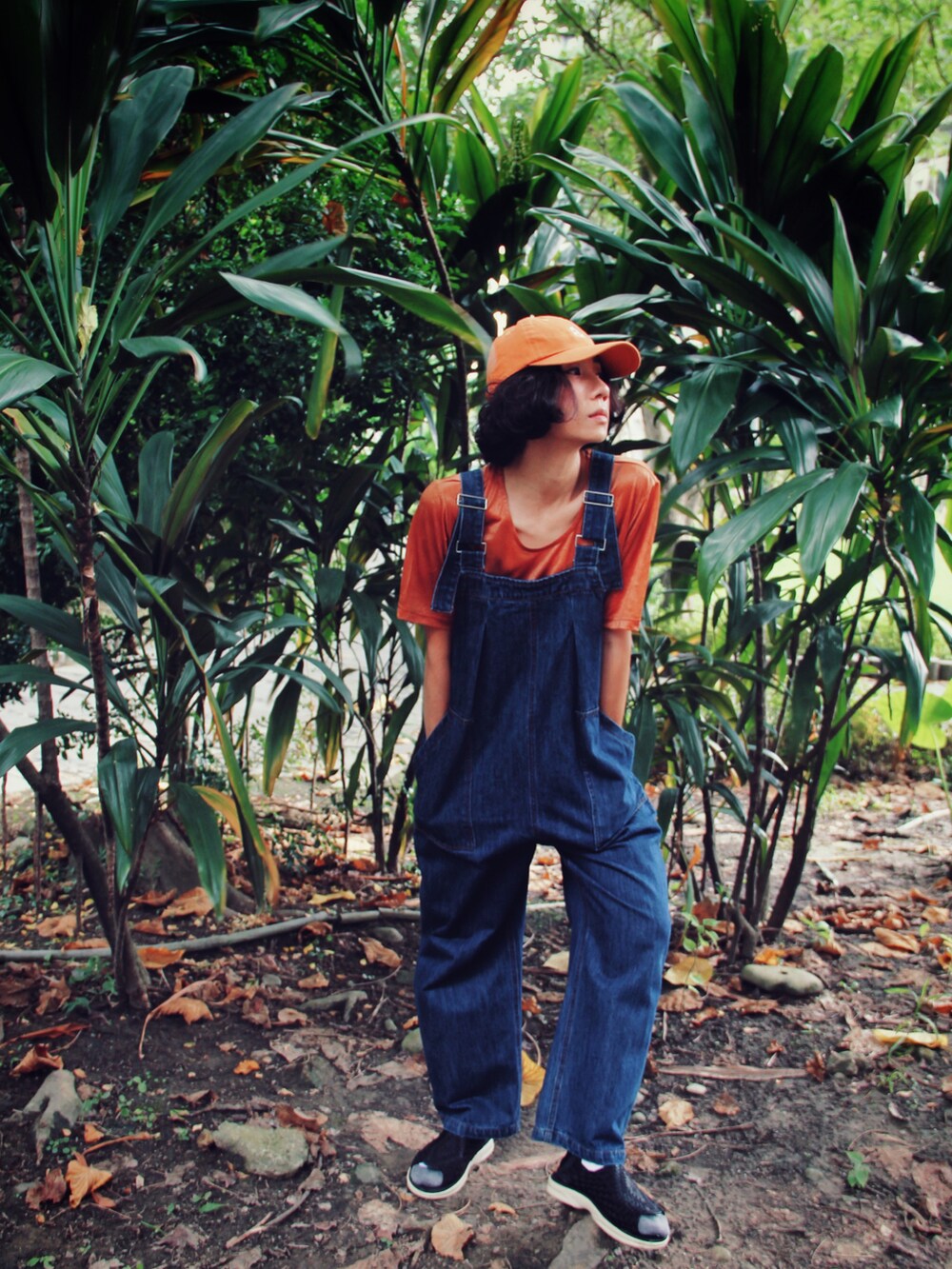 オレンジ系のTシャツ/カットソー、ブルー系のオールインワン・サロペット、オレンジ系のキャップを着用したレディースの夏コーディネートの2枚目の写真