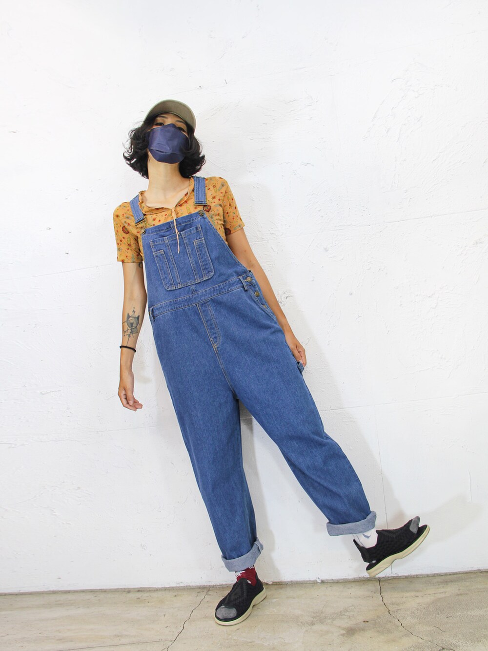ブルー系のつなぎ/オールインワン、オレンジ系のトップス、ベージュ系のキャップを着用したレディースの夏コーディネートの4枚目の写真