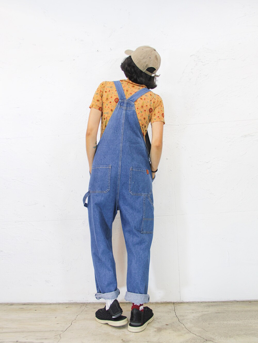 ブルー系のつなぎ/オールインワン、オレンジ系のトップス、ベージュ系のキャップを着用したレディースの夏コーディネートの3枚目の写真