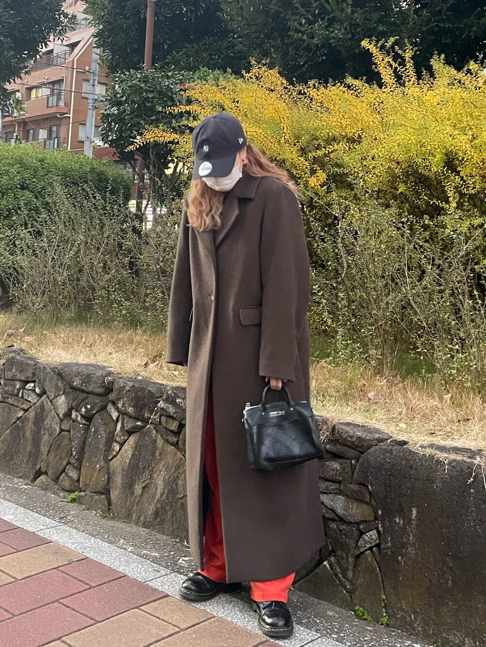 オレンジ系のパンツ、グレー系のワンピース、ブラック系のブーツを着用したレディースの冬コーディネートの2枚目の写真