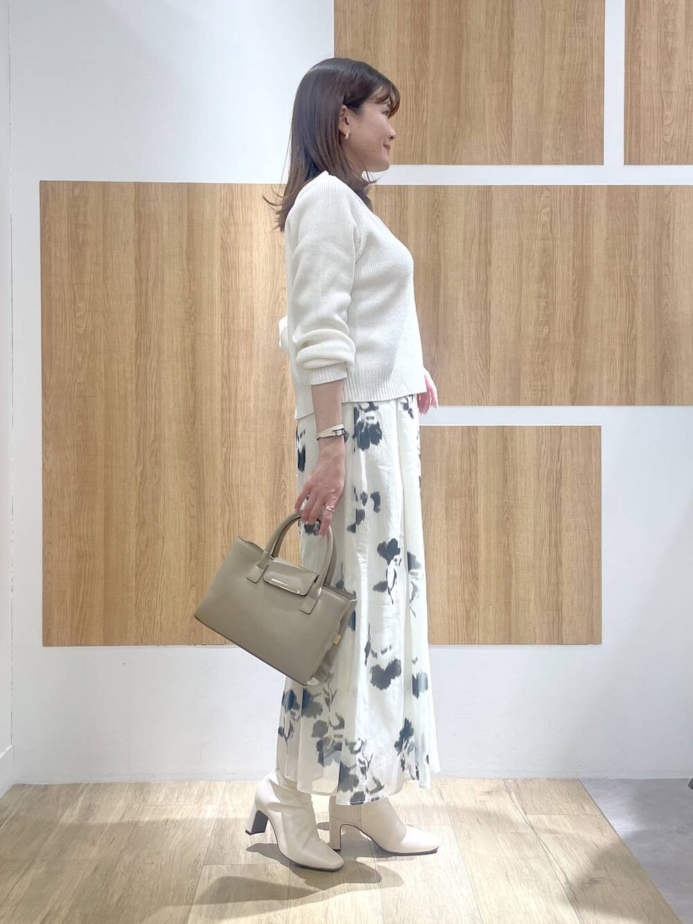 ホワイト系のブーツ、ベージュ系のハンドバッグ、ホワイト系のスカートを着用したレディースの冬コーディネートの3枚目の写真