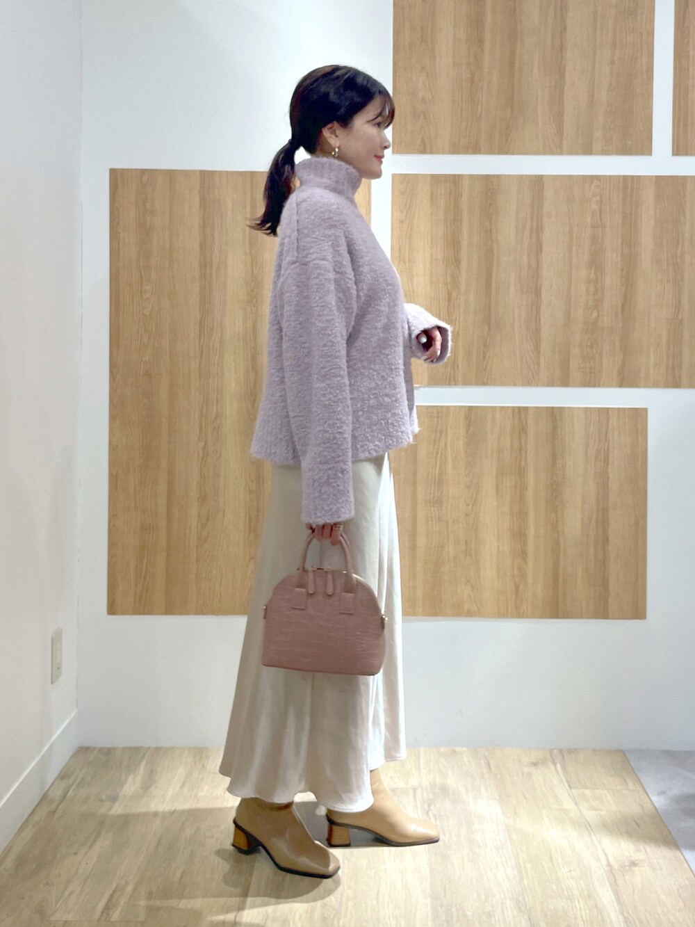 パープル系のニット/セーター、ホワイト系のスカート、ベージュ系のブーツを着用したレディースの冬コーディネートの2枚目の写真