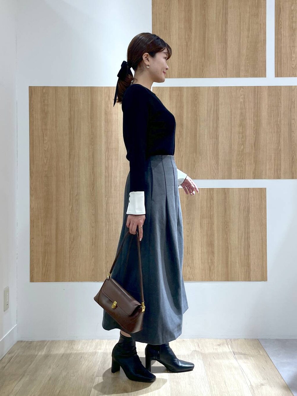 ブラウン系のショルダーバッグ、ブラック系のブーツ、ブラック系のニット/セーターを着用したレディースの冬コーディネートの3枚目の写真