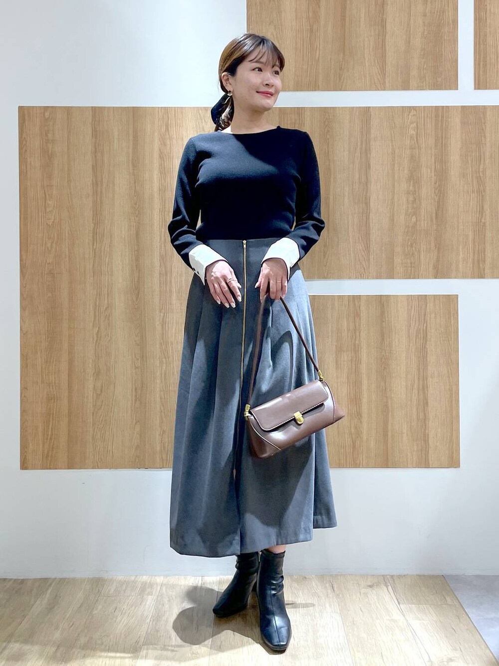 ブラウン系のショルダーバッグ、ブラック系のブーツ、ブラック系のニット/セーターを着用したレディースの冬コーディネートの2枚目の写真