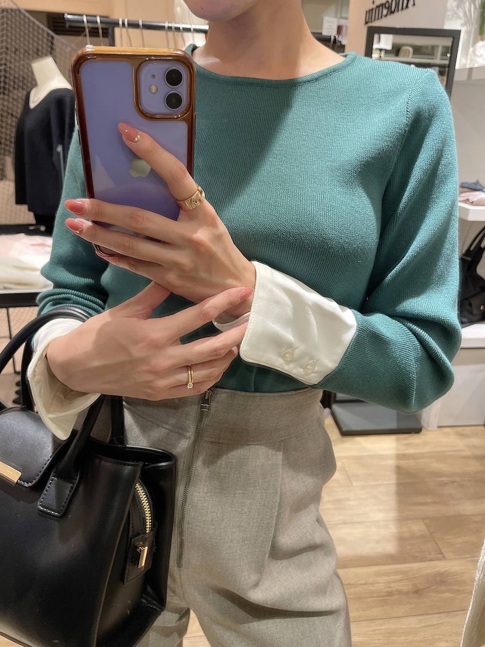 グレー系のスラックス、ブラック系のハンドバッグ、グリーン系のニット/セーターを着用したレディースの秋コーディネートの2枚目の写真