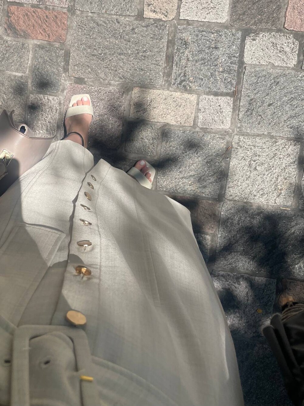 ブラック系のサンダル、ベージュ系のワンピースを着用したレディースの春コーディネートの3枚目の写真