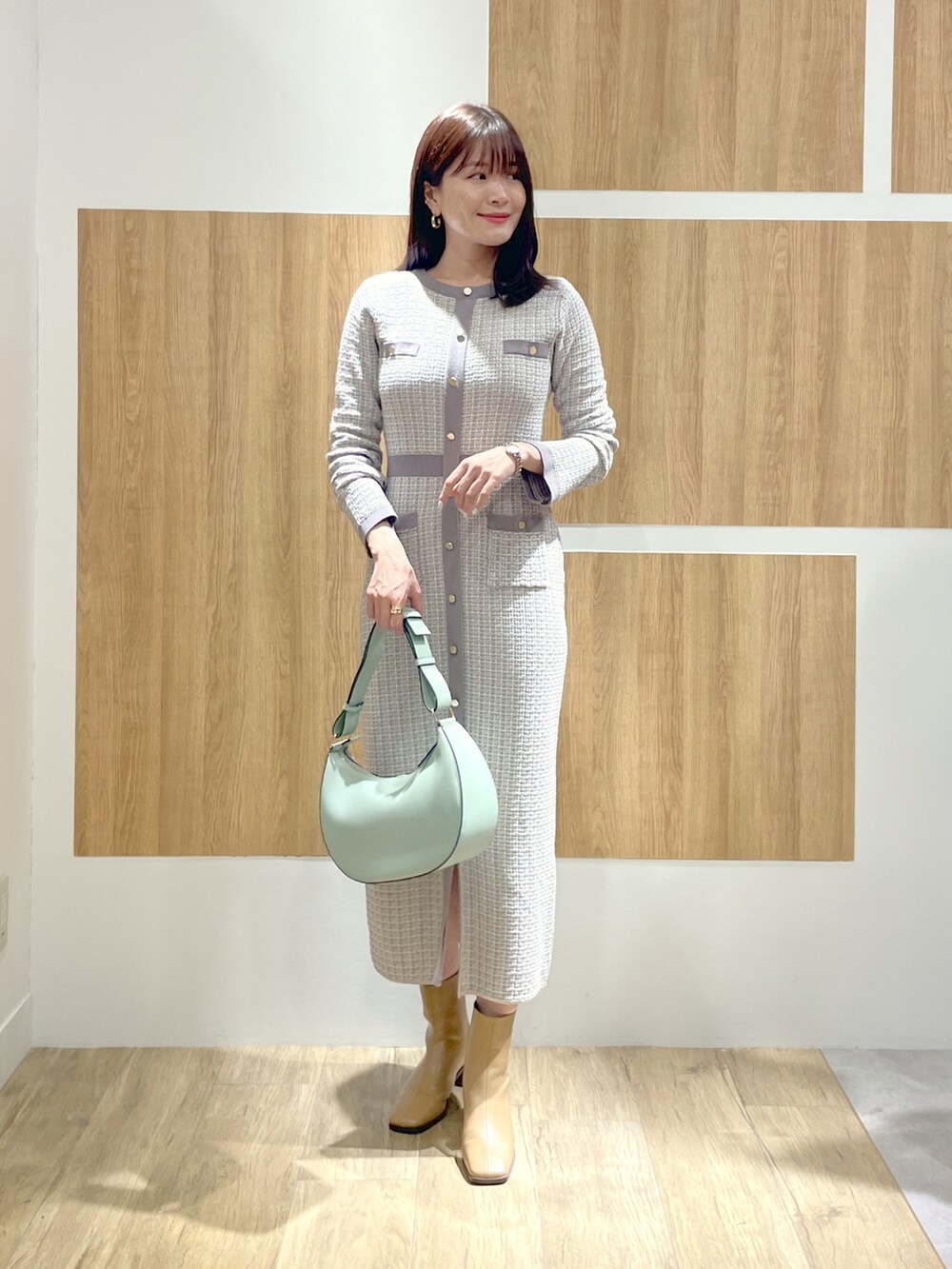 グレー系のチェスターコート、グレー系のワンピース、グリーン系のショルダーバッグを着用したレディースの冬コーディネートの4枚目の写真