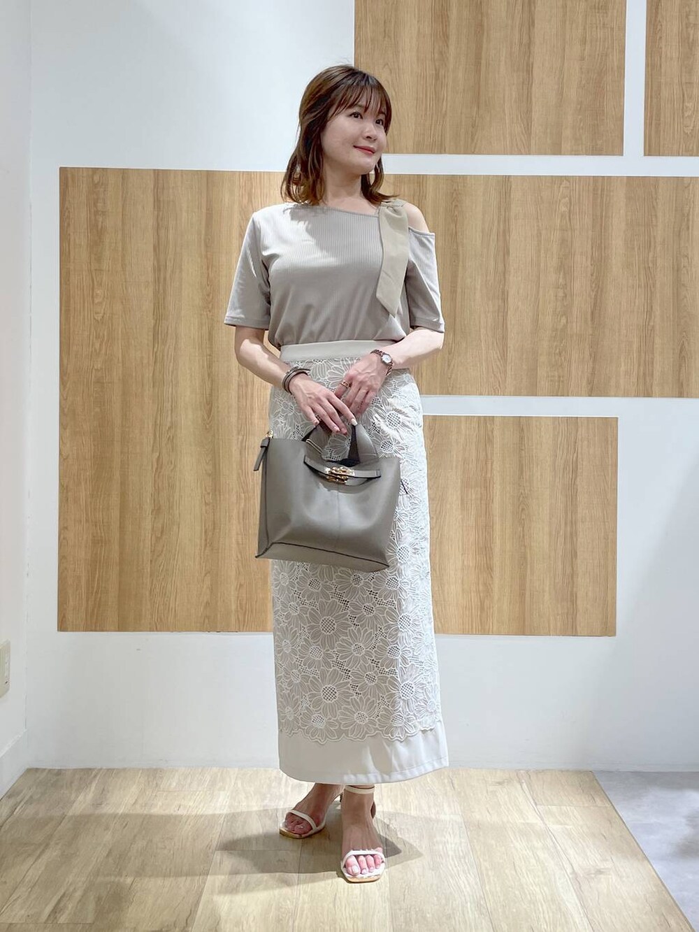 ホワイト系のサンダル、ベージュ系のハンドバッグ、ベージュ系のスカートを着用したレディースの夏コーディネートの2枚目の写真