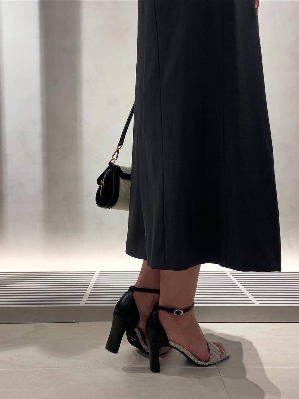 ブラック系のサンダル、ベージュ系のショルダーバッグ、ブラック系のショルダーバッグを着用したレディースの春コーディネートの4枚目の写真