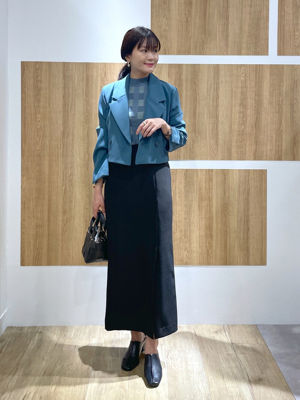 ブルー系のテーラードジャケット、グリーン系のニット/セーター、ブラック系のスカートを着用したレディースの秋コーディネートの2枚目の写真