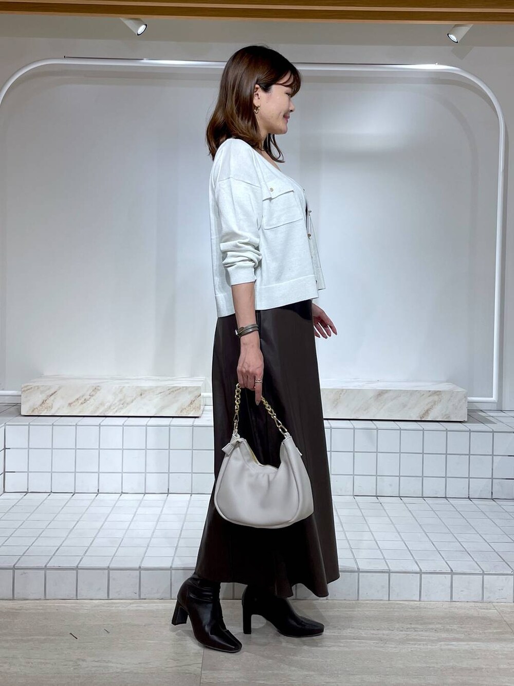 ブラウン系のブーツ、ブラック系のキャミソール、ホワイト系のカーディガン/ボレロを着用したレディースの秋コーディネートの3枚目の写真