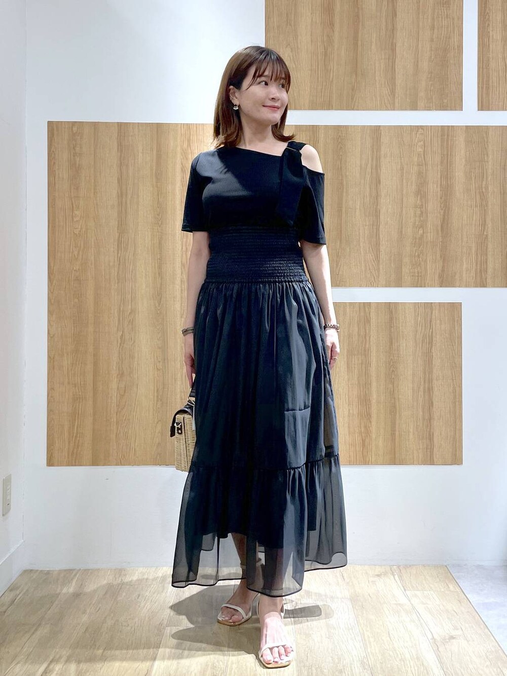 ブラウン系のかごバッグ、ホワイト系のサンダル、ブラック系のスカートを着用したレディースの夏コーディネートの2枚目の写真