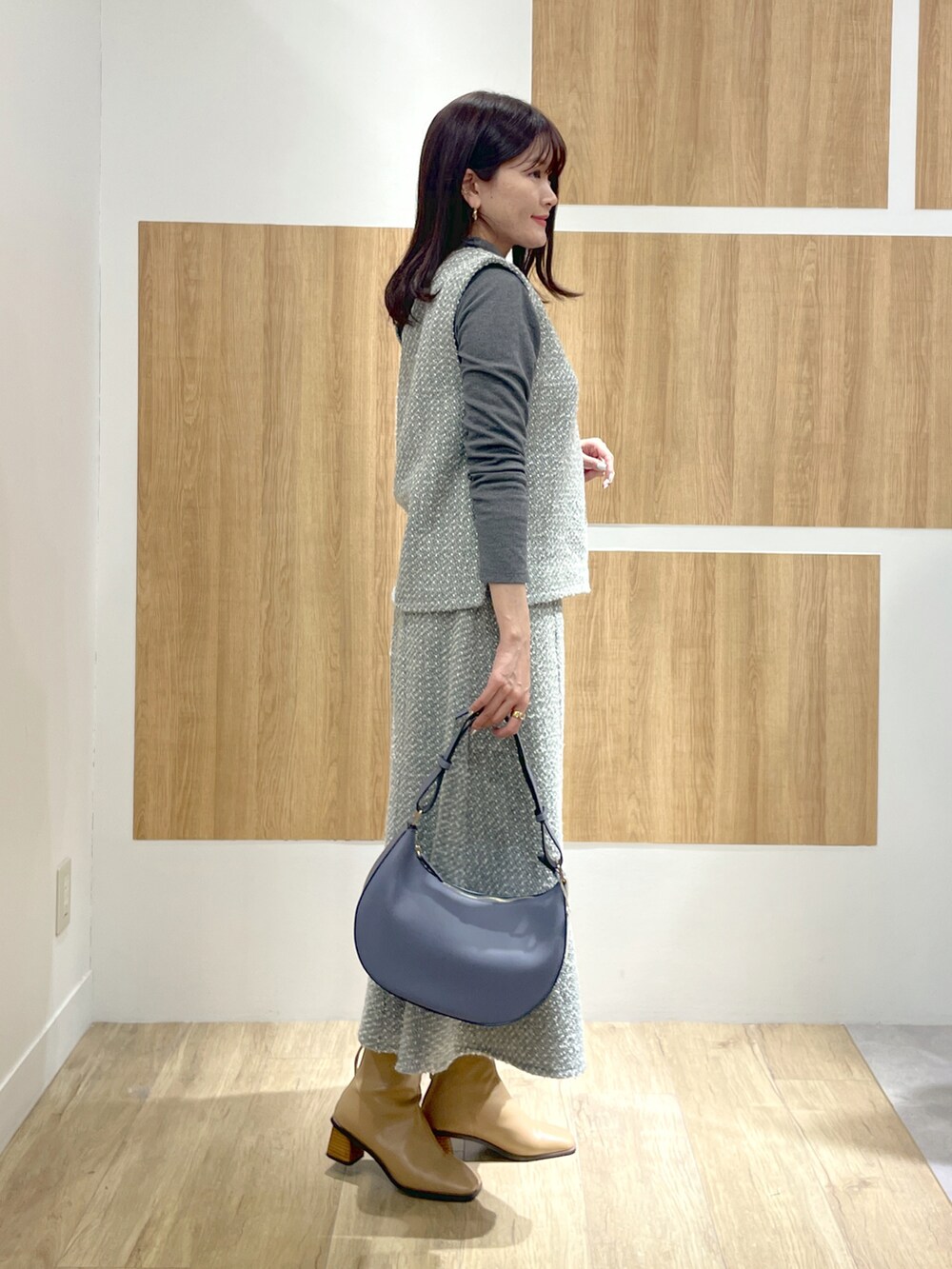 グレー系のTシャツ/カットソー、グレー系のスカート、ブルー系のショルダーバッグを着用したレディースの冬コーディネートの2枚目の写真
