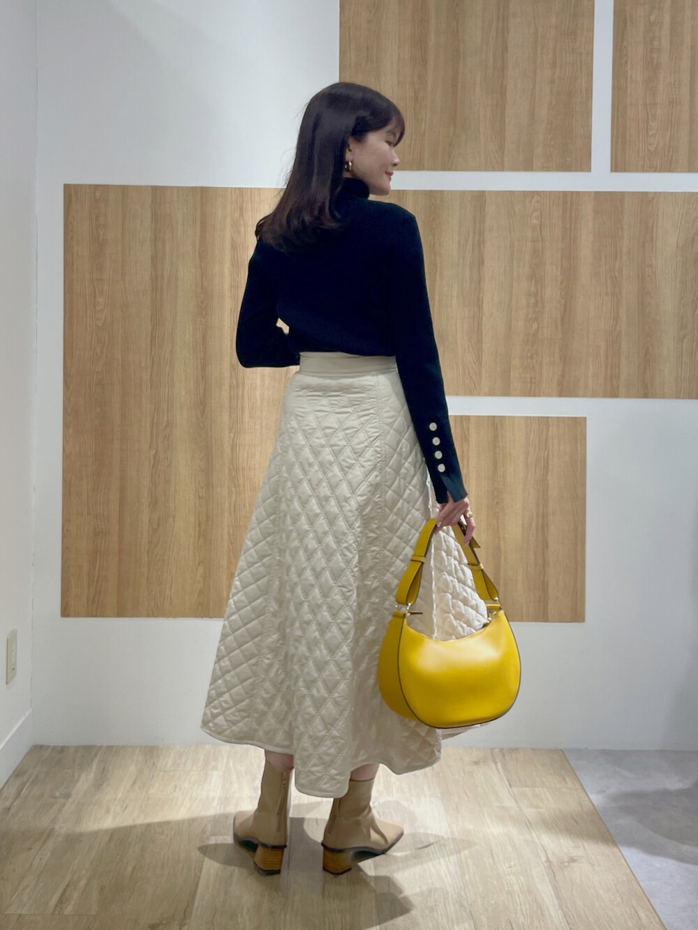 ブラック系のニット/セーター、ベージュ系のスカート、イエロー系のショルダーバッグを着用したレディースの冬コーディネートの3枚目の写真